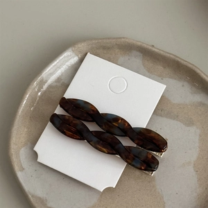 Detail of tortoise shell acetate twist hair clips set on a ceramic plate