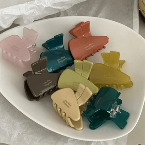 Matte acetate mini triangle hair clips in various colors displayed on a ceramic tray