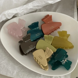 Detail of Morandi-toned matte hair clips on a white ceramic tray with metal springs