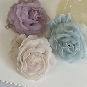 Close-up of soft organza rose hair ties with petal layers and metal letter S charm