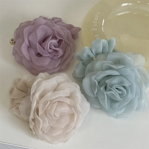 Macro view of pastel layered organza rose hair accessories with delicate pearl accents