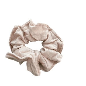Light pink fabric scrunchie with subtle striped texture and soft pleated design on white back