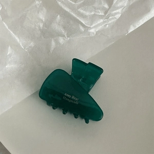 Detail view of a dark green acetate triangle hair claw clip with white logo printing