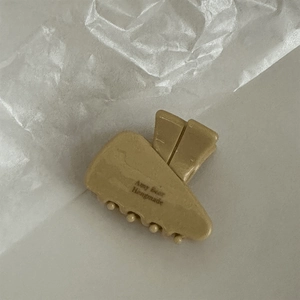 Detail view of small khaki triangle hair claw clip with Any Beer Handmade text logo