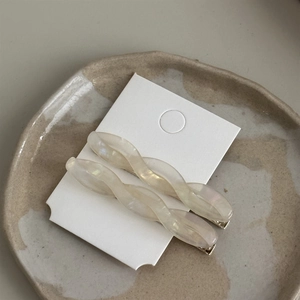 Close-up of champagne twisted acetate hair clips with iridescent mother-of-pearl finish