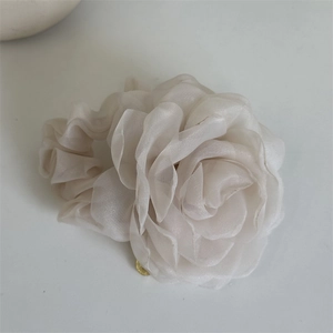 Detailed macro view of the cream-colored organza rose hair scrunchie with gold charm