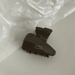 Detailed side view of a dark brown acetate hair claw clip with Amy Bear white lettering