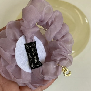 Detail of purple tulle rose scrunchie featuring a handmade label and gold number five charm