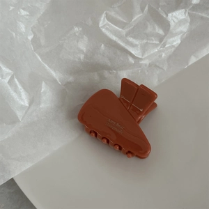Close-up of caramel brown acetate hair claw featuring white handmade text on white background