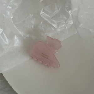 Close-up of pink acetate triangle hair claw clip featuring Amy Bear Handmade text logo