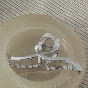 Close-up of a silver wave hair claw clip featuring a large pearl and smooth metallic finish