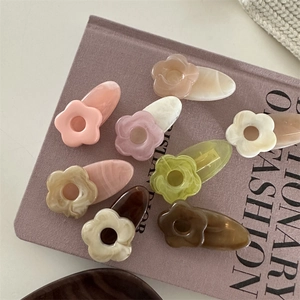 Gros plan de barrettes à fleurs en résine colorée aux tons pastels sur un support élégant