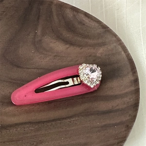 Nahaufnahme der rosa Herz-Haarklammer mit Strass auf Holztablett für feine Details