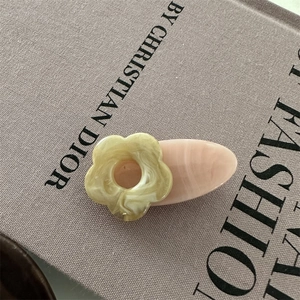 Gros plan d'une pince à cheveux fleurie crème et marbre rose sur un livre décor