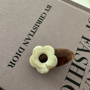 Vue détaillée d'une pince à cheveux fleurie marbrée sur un livre en tissu gris
