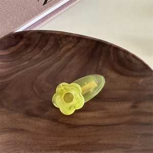 Vue détaillée d'une pince à cheveux fleur jaune en acrylique avec texture marbrée
