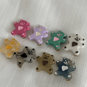 Barrettes à cheveux ours colorées en résine avec détails cœur sur tissu blanc