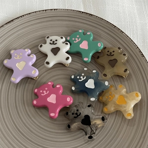 Détail de pinces ours en résine colorée avec motif de cœur dans un plat en céramique