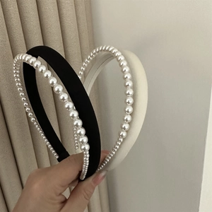 Detailed view of handmade satin pearl headbands in classic black and cream white colors