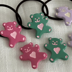 Gros plan d'élastiques ours colorés avec cœurs roses sur fond de tissu blanc doux