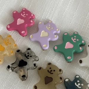 Barrettes à cheveux ours en résine colorée avec détails de cœur sur tissu blanc
