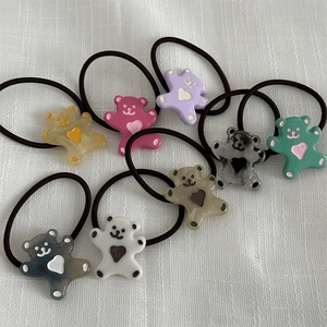 Huit chouchous en résine avec petits ours colorés sur un tissu blanc texturé pour filles