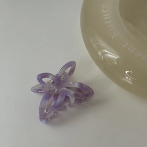 Dettaglio macro della molletta per capelli a farfalla in acetato viola marmorizzato