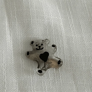 Détail d'une pince à cheveux ours gris marbré avec un cœur noir et un motif sourire