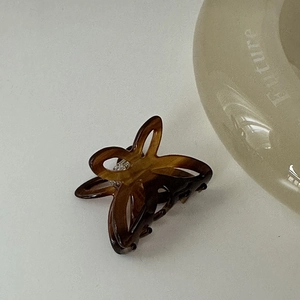 Dettaglio ravvicinato della piccola molletta per capelli a farfalla in acetato tartarugato