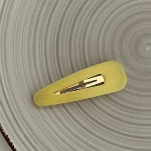 Close-up of yellow teardrop BB hair clip with matte texture on a ceramic plate