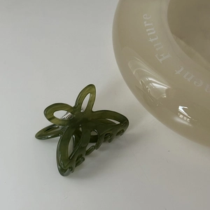 Dettaglio del fermaglio a farfalla in acetato verde scuro con trama marmorizzata