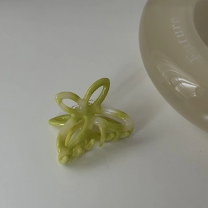 Dettaglio di una piccola pinza per capelli floreale in acetato verde primavera e crema
