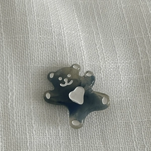 Détail macro d'un accessoire ours gris translucide avec coeur blanc sur fond texturé