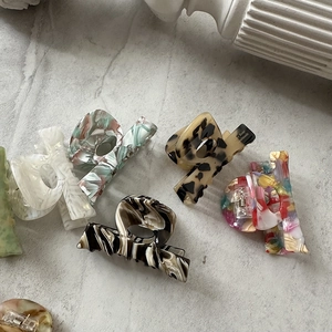 Flat lay of acetate hair claws in marble and tortoiseshell patterns on stone surface