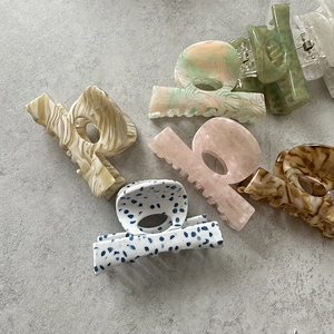 Flat lay showing six colorful acetate marble claw clips for hair styling in macro detail