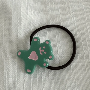 Détail d'élastique à cheveux ours vert mignon sur fond de tissu blanc texturé