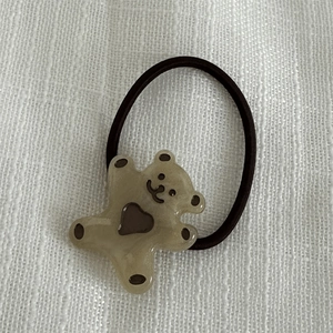 Détail de l'élastique à cheveux ours en résine marron clair avec cœur sur lin blanc
