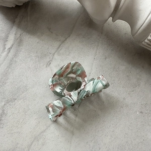 Close-up of marble pattern acetate hair claw clip with glossy green and pink texture