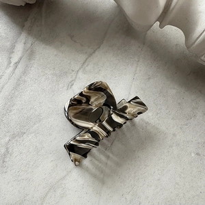 Detailed macro view of the marble texture and curved teeth on this elegant hair claw clip