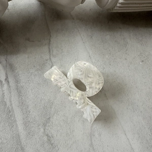 Detail view of a marble pattern acetate hair claw clip on a gray stone surface
