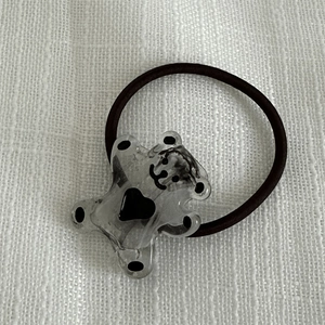 Détail d'un élastique à cheveux marron orné d'un pendentif ours en acrylique translucide