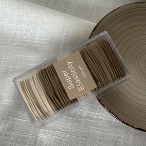 Detail of high elasticity hair ties in earth tones set in transparent acrylic gift box