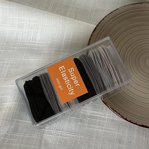 Detail view of 10 high elasticity hair ties in a transparent box with orange label