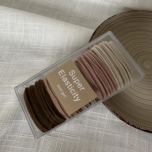 Macro shot of 50 elastic hair ties in earth tones neatly packed in a transparent box