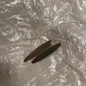 Détail de deux barrettes à cheveux en métal argenté sur un fond blanc texturé