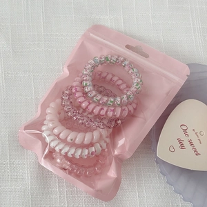 Close-up of pink gradient spiral hair coils in a cute translucent zipper storage bag