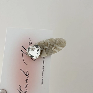 Close-up of acetic acid hair clip with marble pattern and large heart rhinestone