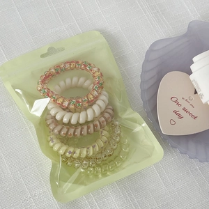 Colorful spiral hair ties set in frosted packaging on a white textured background