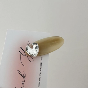 Detail of handmade acetate hair clip featuring a heart crystal and engraved branding
