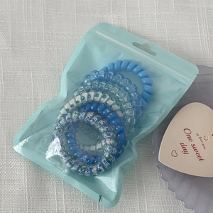 Close-up of blue gradient spiral hair ties in a frosted zipper bag on white fabric
